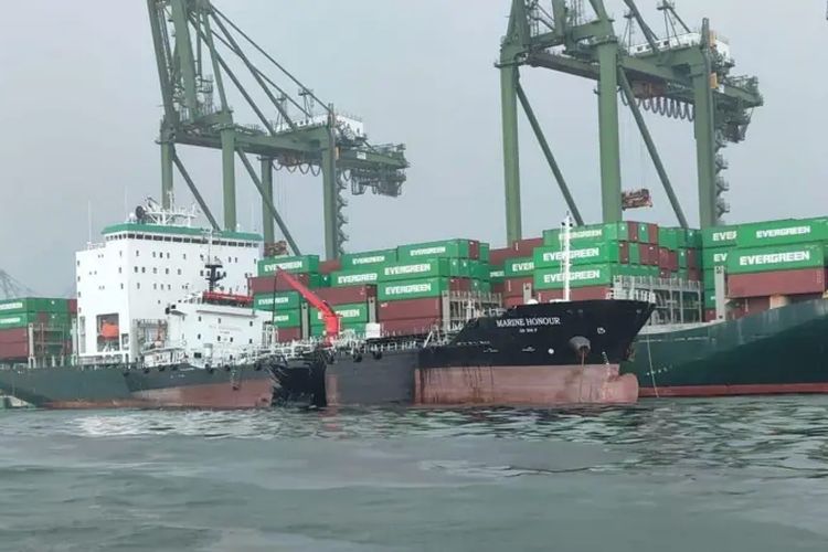 Air yang berminyak dan berwarna gelap mengelilingi kapal yang tertabrak.
