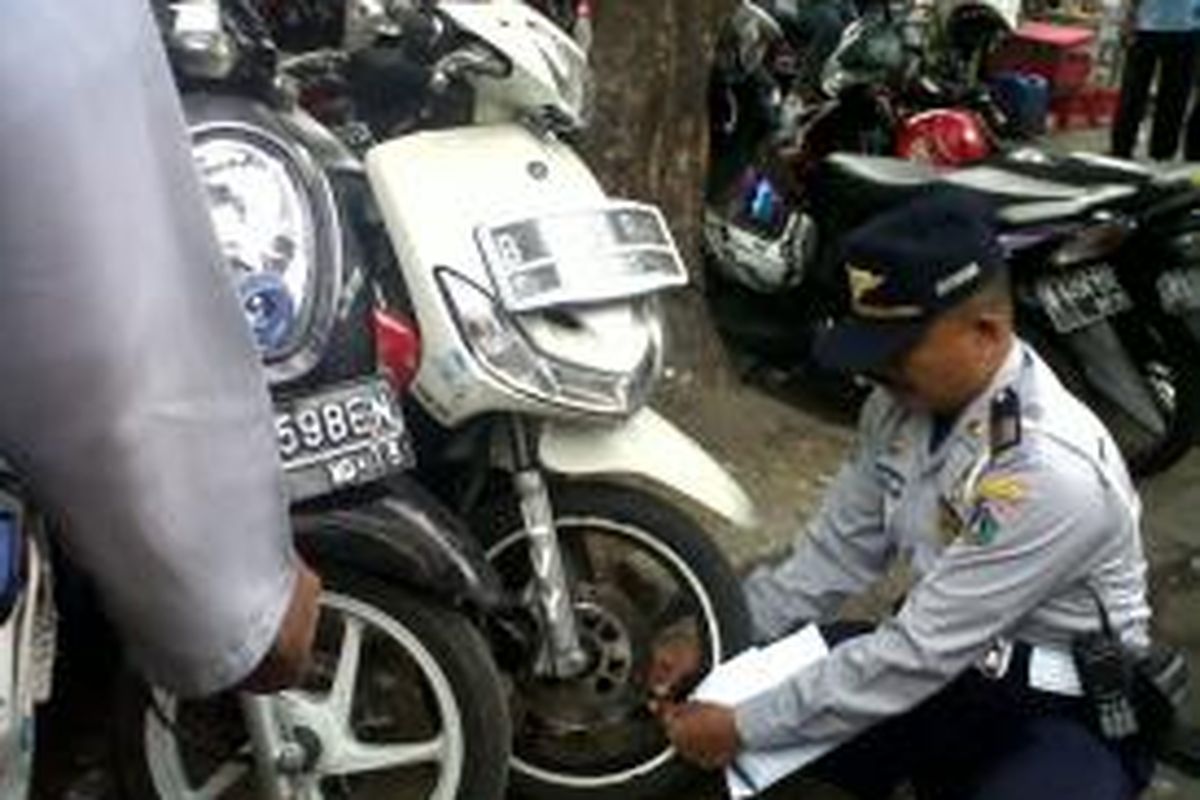 Petugas Suku Dinas Perhubungan DKI Jakarta Pusat mencabut pentil ban sepeda motor dalam operasi penertiban parkir liar di sejumlah tempat di Jakarta Pusat, Rabu (2/10/2013).

