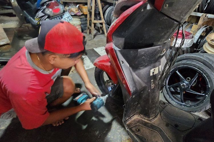 Ilustrasi teknisi memperbaiki suspensi motor.