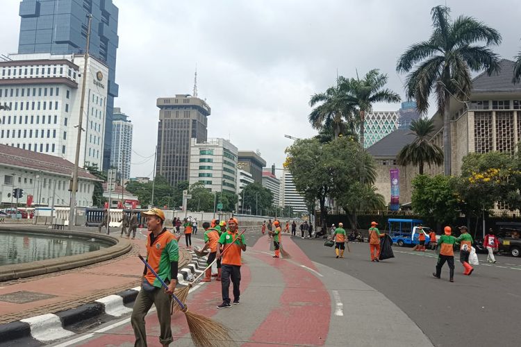 Petugas PPSU dan Dinas Lingkungan Hidup berjibaku bersihkan sampah di Kawasan Patung Kuda, Monas, Jakarta Pusat, Senin (1/5/2023) siang.