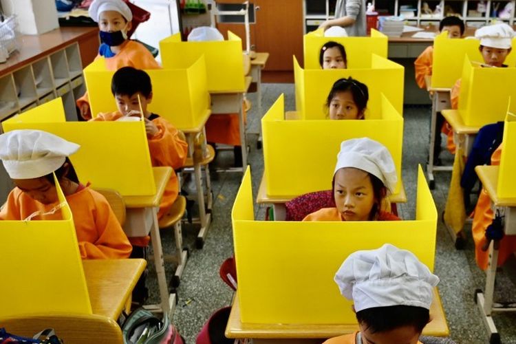 Siswa makan siang di atas meja dengan sekat plastik sebagai langkah pencegahan penyebaran virus corona COVID-19 di Sekolah Dasar Dajia di Taipei pada 29 April 2020.