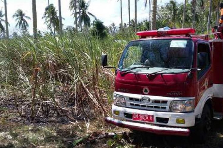 Mobil pemadam kebakaran berupaya memadamkan api di lahan tebu di kabupaten Gorontalo. Kebun ini merupakan kerjasama antara warga desa dengan pabrik gula Rajawali