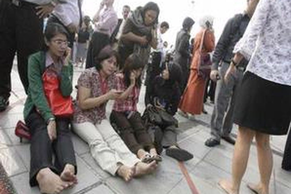 Karyawan di Plaza Mandiri, Jakarta, menyelamatkan diri ke lapangan terbuka setelah gempa yang berpusat di Tasikmalaya turut mengguncangkan kawasan ibukota, Rabu (2/9). Gempa berpusat di 140 kilometer barat daya Tasikmalaya berkekuatan 7,3 skala richter. Data sementara hingga kini korban tewas akibat gempa mencapai 25 orang. 