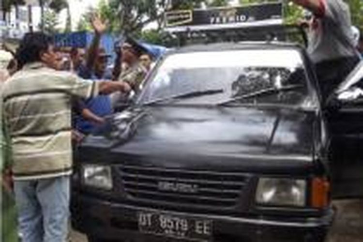 Seorang polisi berusaha menenangkan para sopir, yang akan menyandera mobil yang telah dimodifikasi dan ikut antrian solar di salah satu SPBU di Kendari.