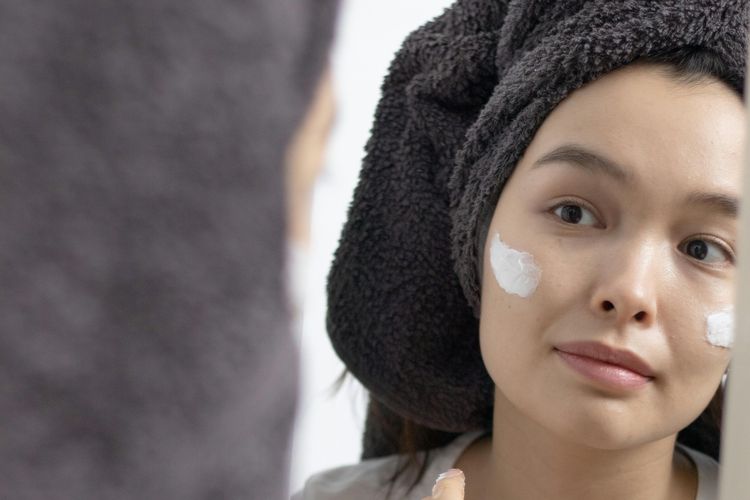 Ilustrasi perempuan mengaplikasikan skincare pada wajah