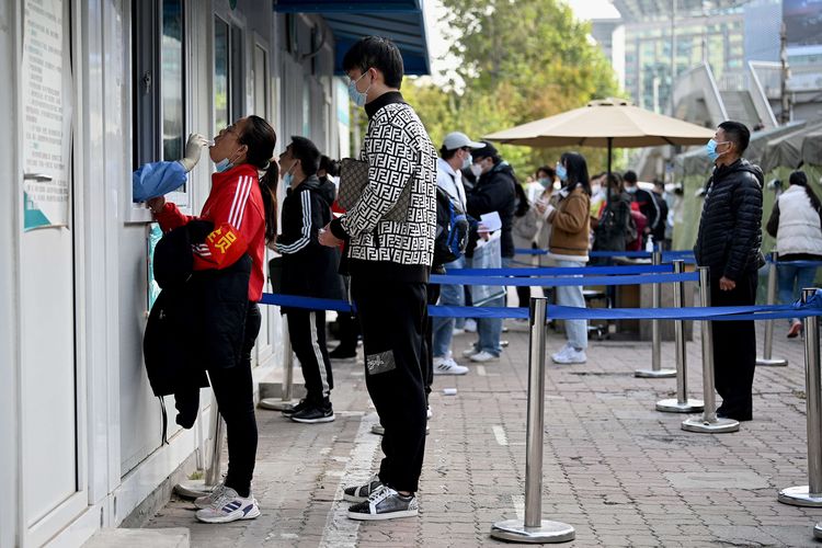 Petugas kesehatan mengambil sampel swab untuk tes Covid-19 dari seorang wanita di stasiun pengumpulan asam nukleat di Beijing, China, Senin (25/10/2021). Penyebaran Covid-19 di China kembali menjadi peringatan setelah klaster baru terkait sekelompok wisatawan ditemukan 17 Oktober lalu.