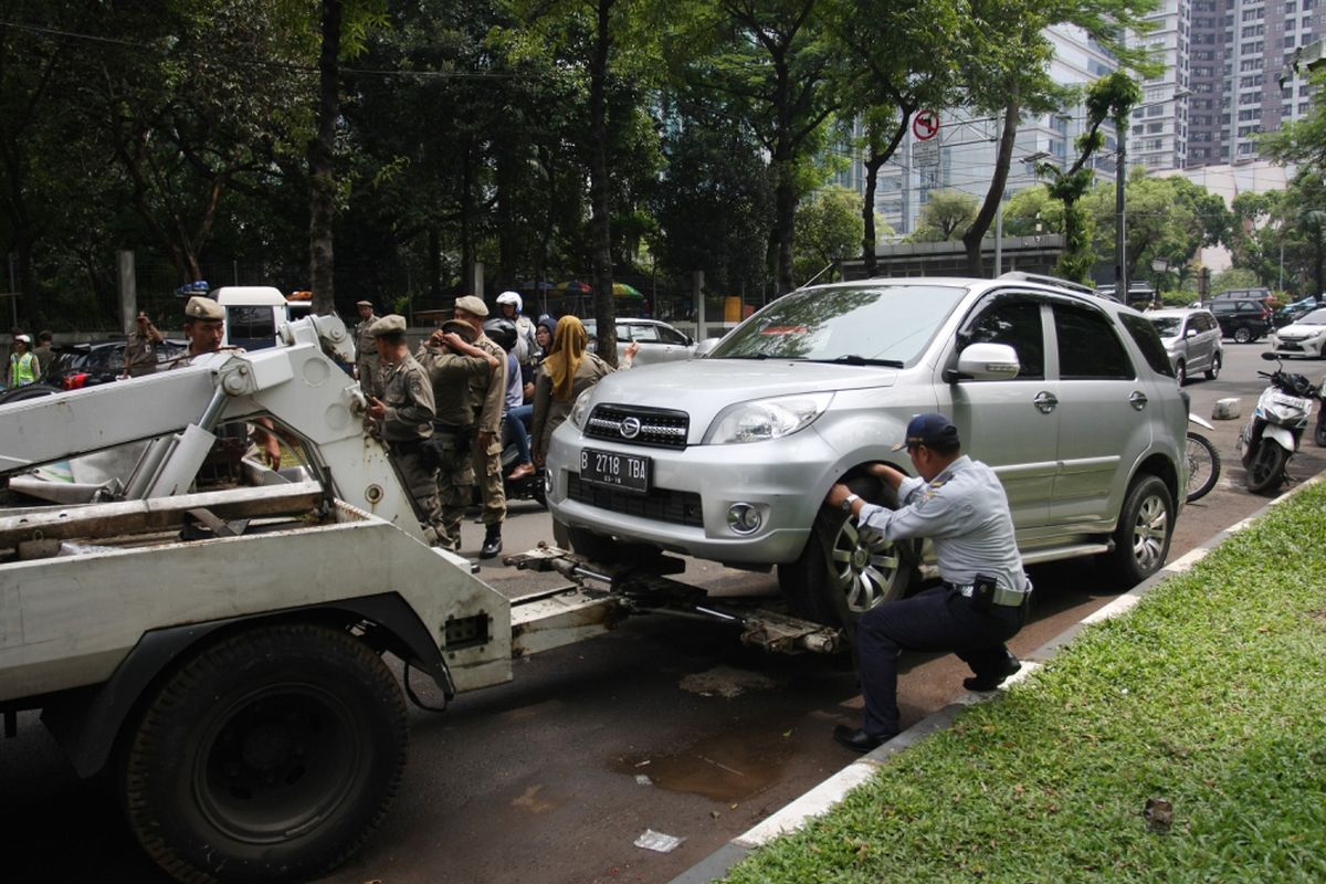 Petugas Dinas Perhubungan DKI Jakarta menderek mobil yang parkir di bahu jalan di kawasan Jalan Widya Chandra, Jakarta, Selasa (10/10). Dalam razia tersebut petugas melakukan pencabutan pentil kendaraan yang parkir di bahu jalan dan trotoar karena dinilai mengganggu pengguna jalan sekaligus untuk membuat jera para pelaku. ANTARA FOTO/Reno Esnir/kye/17.