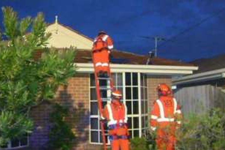 Petugas bantuan memperbaiki atap rumah yang rusak karena badai hari Senin (21/11/2016) di Victoria.
