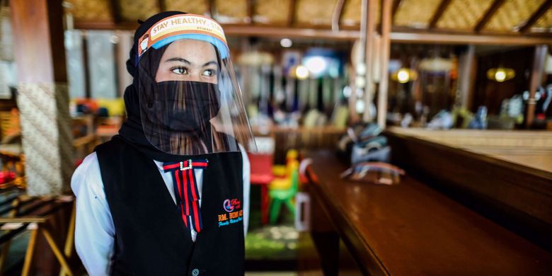 Pelayan menggunakan alat pelindung diri wajah, masker dan sarung tangan saat menunggu pengunjung di Rumah Makan Bumi Aki, Pajajaran, Kota Bogor, Jawa Barat, Selasa (2/6/2020). Sejumlah rumah makan di Kota Bogor mulai membuka layanan makan di tempat dengan protokol kesehatan ketat setelah penerapan Pembatasan Sosial Berskala Besar (PSBB) Kota Bogor memasuki masa transisi hingga tanggal 4 Juni 2020 guna mengatasi pandemi COVID-19.