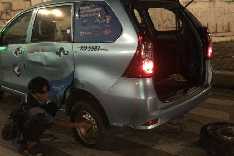 Sopir taksi sedang mengganti ban yang sobek akibat kecelakaan dengan motor di Jalan Raya Sawangan tepatnya di persimpangan Tol Desari, Rangkapan Jaya Baru, Pancoran Mas, Jakarta Selatan pada Minggu (20/6/2021) pagi.