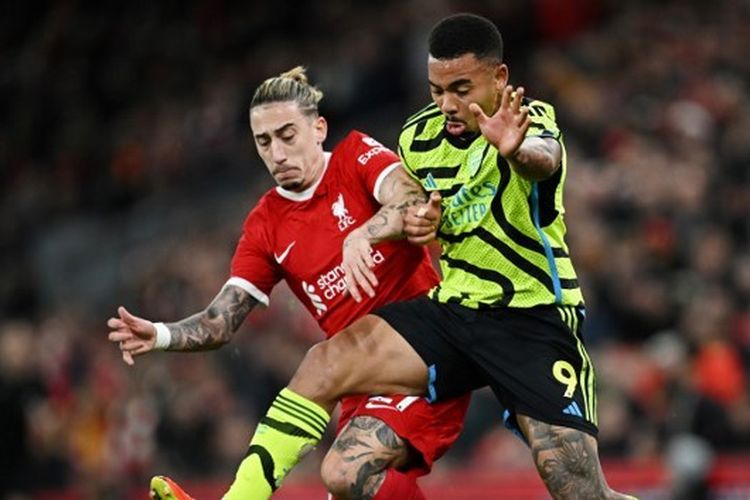 Bek kiri Liverpool, Kostas Tsimikas (kiri), berebut bola dengan striker Arsenal, Gabriel Jesus, dalam laga pekan ke-18 Liga Inggris 2023-2024 yang digelar di Stadion Anfield pada Minggu (24/12/2023). Tsimikas mengalami cedera patah tulang selangka usai tak sengaja bertabrakan dengan Juergen Klopp. (Foto oleh PAUL ELLIS/AFP)