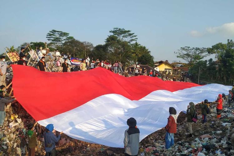 Komunitas Lingkungan Tasikmalaya membentangkan bendera raksasa di atas tumpukan sampah memaknai memerangi informasi hoaks sebagai sampah dengan cara memperkuat persatuan dan kesatuan di Hari Kemerdekaan RI di TPA Ciangir, Kota Tasikmalaya, Minggu (15/8/2021).