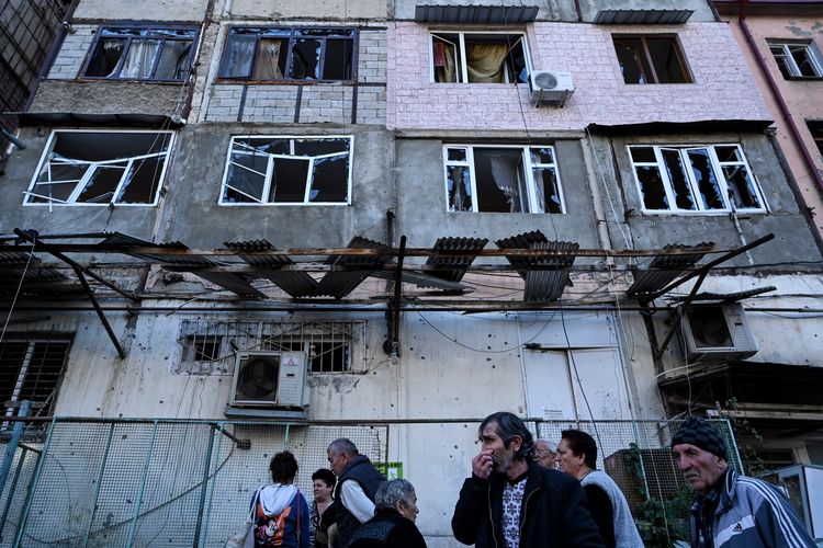 Orang-orang berkumpul di depan sebuah gedung apartemen yang diduga rusak oleh penembakan baru-baru ini di kota utama Stepanakert di wilayah Nagorno-Karabakh pada 3 Oktober 2020, selama pertempuran yang sedang berlangsung antara Armenia dan Azerbaijan atas wilayah yang disengketakan.