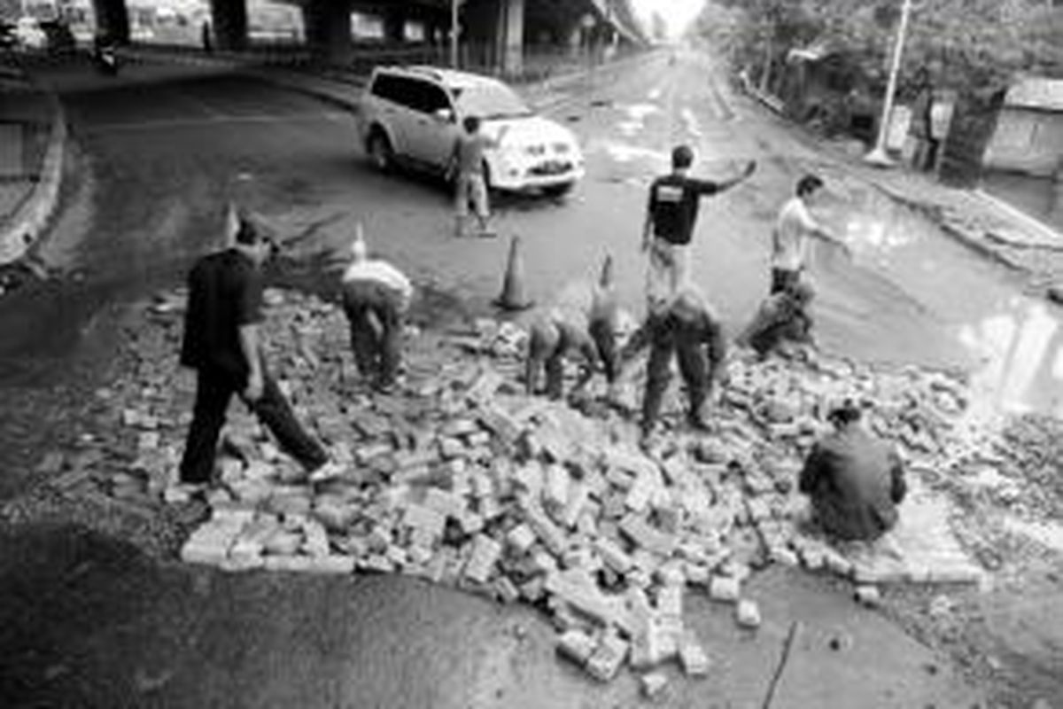 Pekerja menambal lubang besar di Jalan Puri Lingkar Luar, Puri Kembangan, Jakarta Barat, Senin (27/1). Lubang besar di jalan yang rusak itu untuk sementara ditutup dengan paving block agar kendaraan bisa melintas.