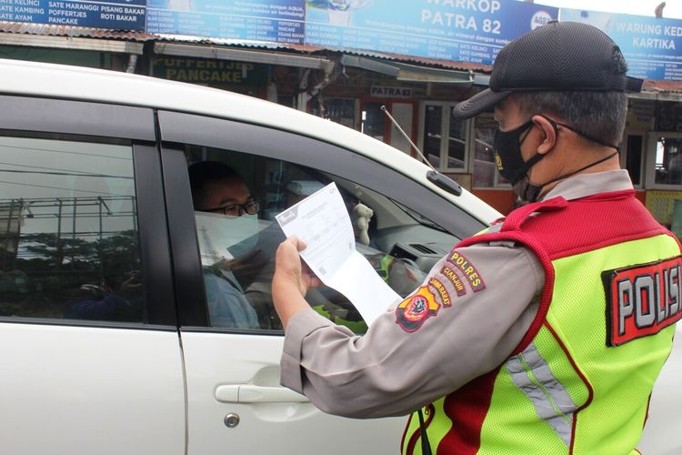 Seorang anggota polisi memeriksa surat keterangan hasil antigen seorang pengendara dalam giat penyekatan di check point Seger Alam, Ciloto Puncak, Kabupaten Cianjur, Jawa Barat, Kamis (29/4/2021)