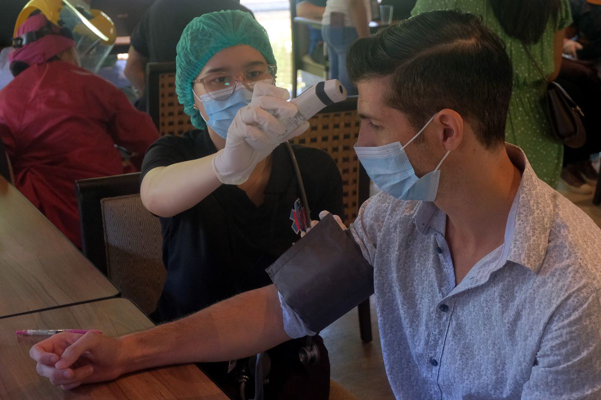 Petugas kesehatan memeriksa suhu tubuh warga negara asing (WNA) yang menjalani vaksinasi dosis kedua di wilayah Sanur, Denpasar, Bali, Selasa (22/6/2021). Sebanyak 537 orang WNA yang menerima vaksin dosis pertama pada bulan Maret 2021 tersebut saat ini menjalani vaksinasi dosis kedua untuk mencapai herd immunity dan persiapan kawasan zona hijau bebas Covid-19 di wilayah Sanur, Denpasar.