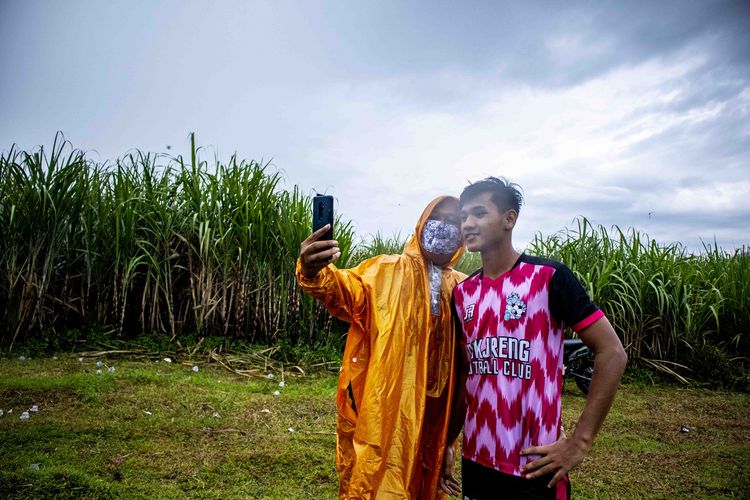 Pemain Arema FC yang juga Pemain Timnas Indonesia U19, Titan Agung saat foto bersama salah satu penonton di laga amal nutuk korban bencana di Sulawesi dan Kalimantan di Lapangan Desa Dampit, Kabupaten Malang, Jawa Timur, Minggu (24/01/2021) sore.