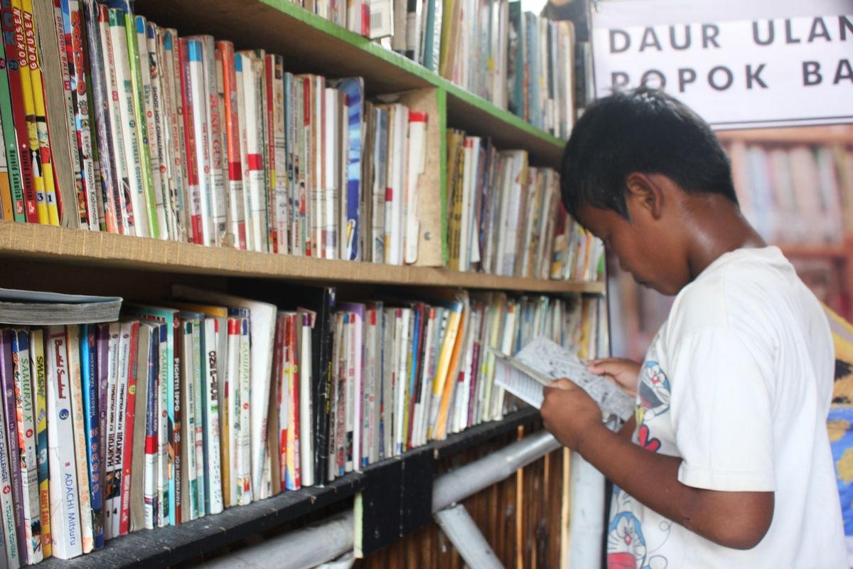 Seorang anak sedang serius membaca buku di Saung Baca Cianjur, Jawa Barat yang didirikan mantan cleaning service, Sandi Mulyadi (36)