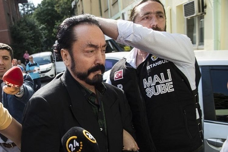 Foto arsip yang diambil pada 11 Juli 2018 saat petugas polisi Turki mengawal televangelis dan pemimpin sekte, Adnan Oktar (tengah) alias Harun Yahya di Istanbul, saat dia ditangkap atas tuduhan penipuan. Dia terbukti telah melakukan kejahatan seksual yang mengakibatkannya dipenjara lebih dari 1.000 tahun.