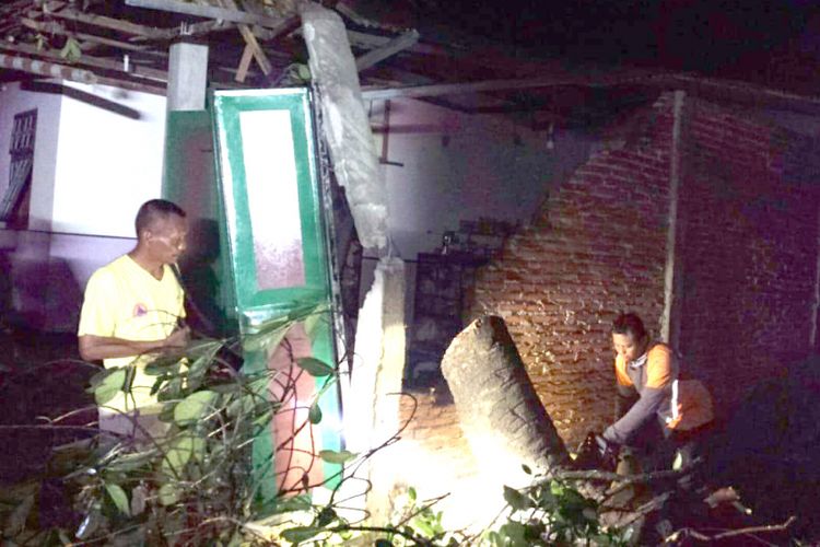 Relawan dari BPBD Jombang Jawa Timur, melakukan pembersihan dan pemotongan pohon tumbang yang menimpa rumah Kholiq, warga Dusun Nglerep, Desa Kwaron, Kabupaten Jombang, Sabtu (24/11/2018) malam.