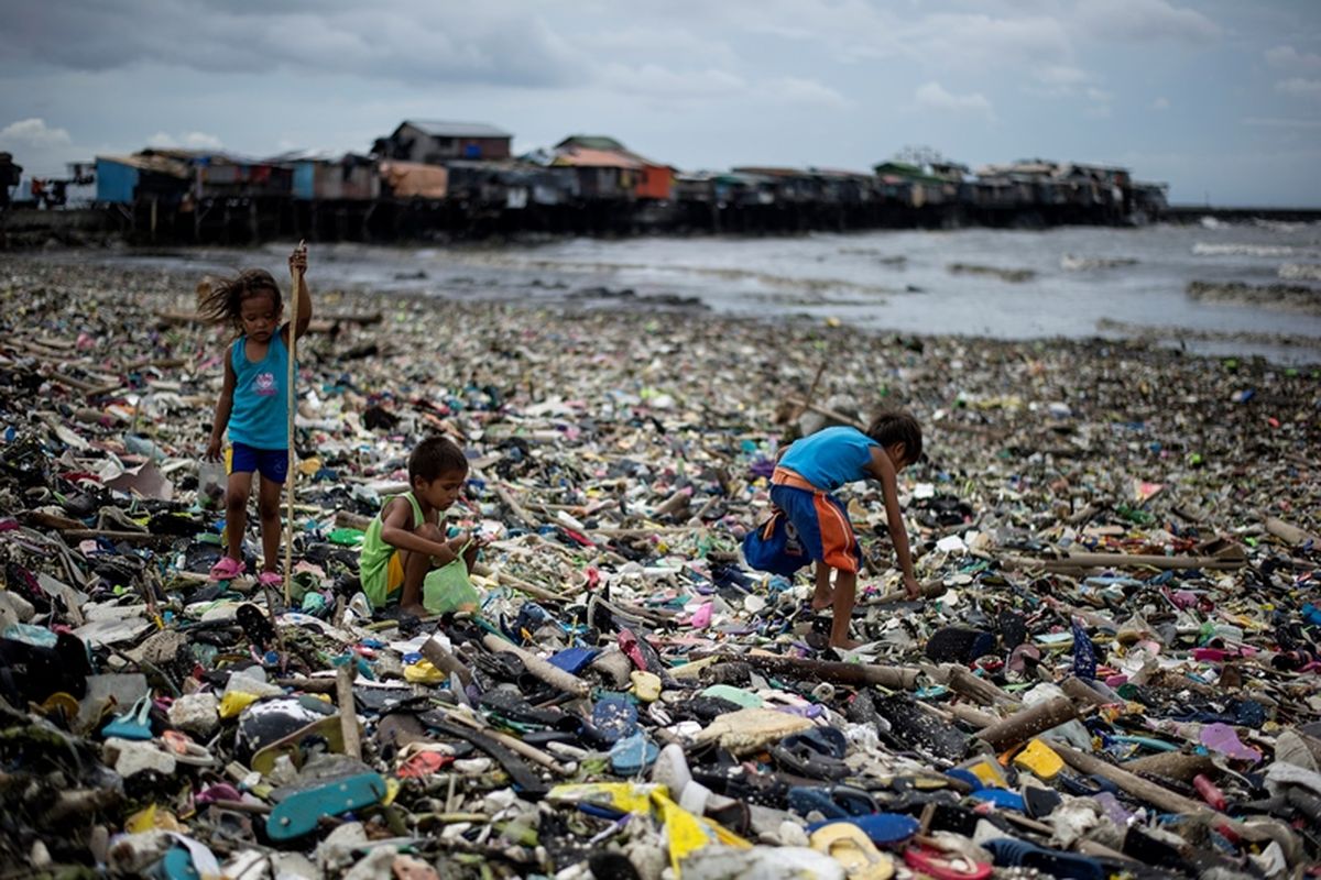 Anak-anak mengumpulkan botol air plastik di antara sampah yang terbawa ke darat akibat gelombang badai topan Haima di Teluk Manila pada 20 Oktober 2016. (AFP/Noel Celis)