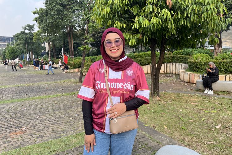 Amelia, salah satu penonton pertandingan bola Indonesia vs China, mengenakan jersey dan hijab burgundy di Gelora Bung Karno, Jakarta Pusat, Kamis (5/6/2025.