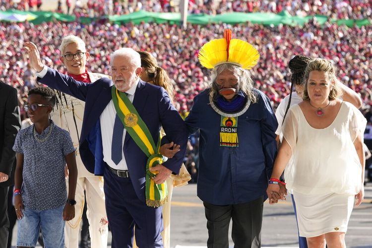 Luiz Inacio Lula da Silva melambaikan tangannya setibanya di Istana Planalto bersama kelompok yang mewakili berbagai segmen masyarakat setelah ia dilantik sebagai presiden baru di Brasilia, Brasil, Minggu (1/1/2023).