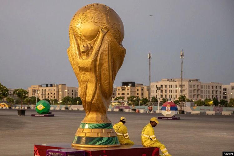 Pekerja duduk di samping replika Piala Dunia di luar Stadion Lusail jelang Piala Dunia, di Lusail, Qatar, 10 November 2022.