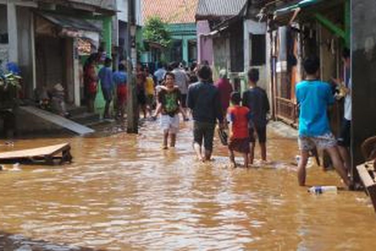 Warga Ulujami berjalan melintasi genangan air yang masih merendam sebagian lokasi meski sudah surut dibanding sebelumnya. Jumat (9/8/2013).