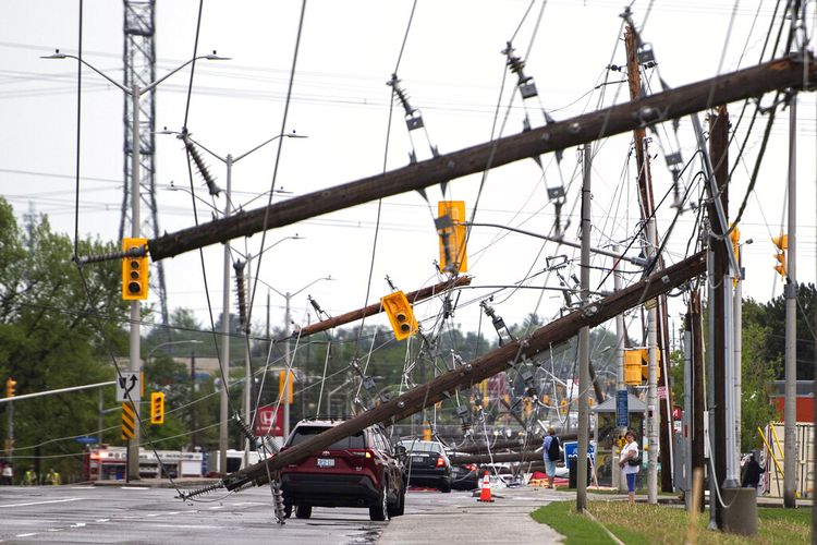 Sebuah kendaraan terlihat di antara kabel listrik dan tiang listrik yang tumbang setelah badai besar di Merivale Road di Ottawa, Kanada, pada Sabtu, 21 Mei 2022.