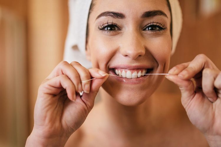 Ilustrasi membersihkan gigi dengan dental floss atau benang gigi. 