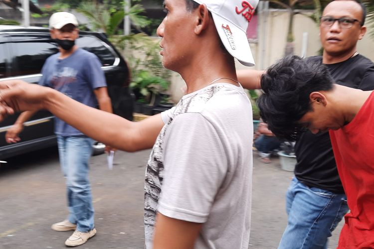 Salah satu pelaku (baju merah) tawuran antarpemuda di Jalan Prumpung Sawah, Kelurahan Cipinang Besar Utara, Kecamatan Jatinegara, Jakarta Timur, yang mengakibatkan satu korban tewas, digiring ke Mapolsek Jatinegara, Jumat (1/4/2022).
