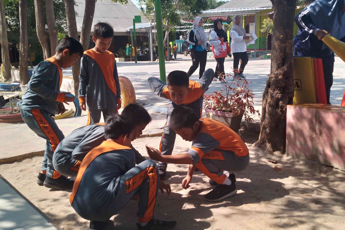 Siswa bermain dengan riang di bawah pohon.