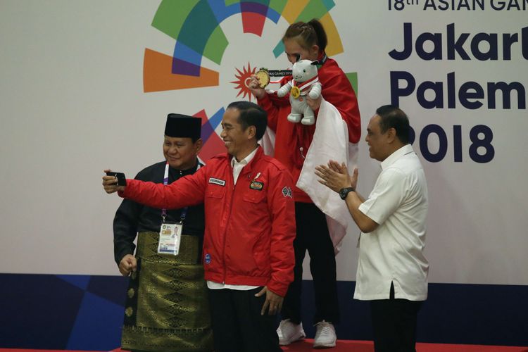 Presiden Republik Indonesia, Joko Widodo dan Presiden Persekutuan Pencak Silat Antarbangsa (Persilat), Prabowo Subianto memberikan medali pada pesilat putri Indonesia Wita Wewey pada pertandingan partai final pencak silat Asian Games 2018 di Padepokan Pencak Silat, TMII, Jakarta, Rabu (29/8/2018). Wita Wewey, meraih medali emas pada partai final kelas B putri 50 kg sampai 55 kg mengalahkan atlet pencak silat asal Vietnam, Tran Thi Them.