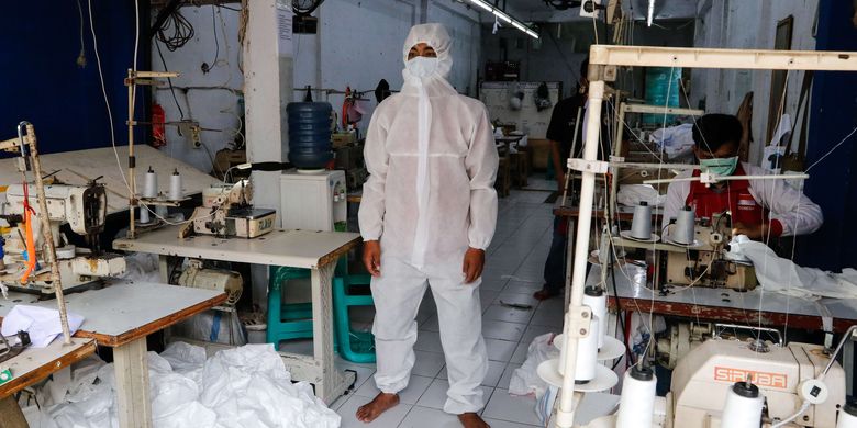 Pekerja menunjukkan alat pelindung diri buatan konveksi milik Riswan Halomoan di kawasan PIK, Penggilingan, Jakarta Timur, Kamis (26/3/2020). Konveksi ini memproduksi 1000 APD perhari pesanan dari berbagai rumah sakit untuk tenaga medis yang menangani pasien COVID-19.