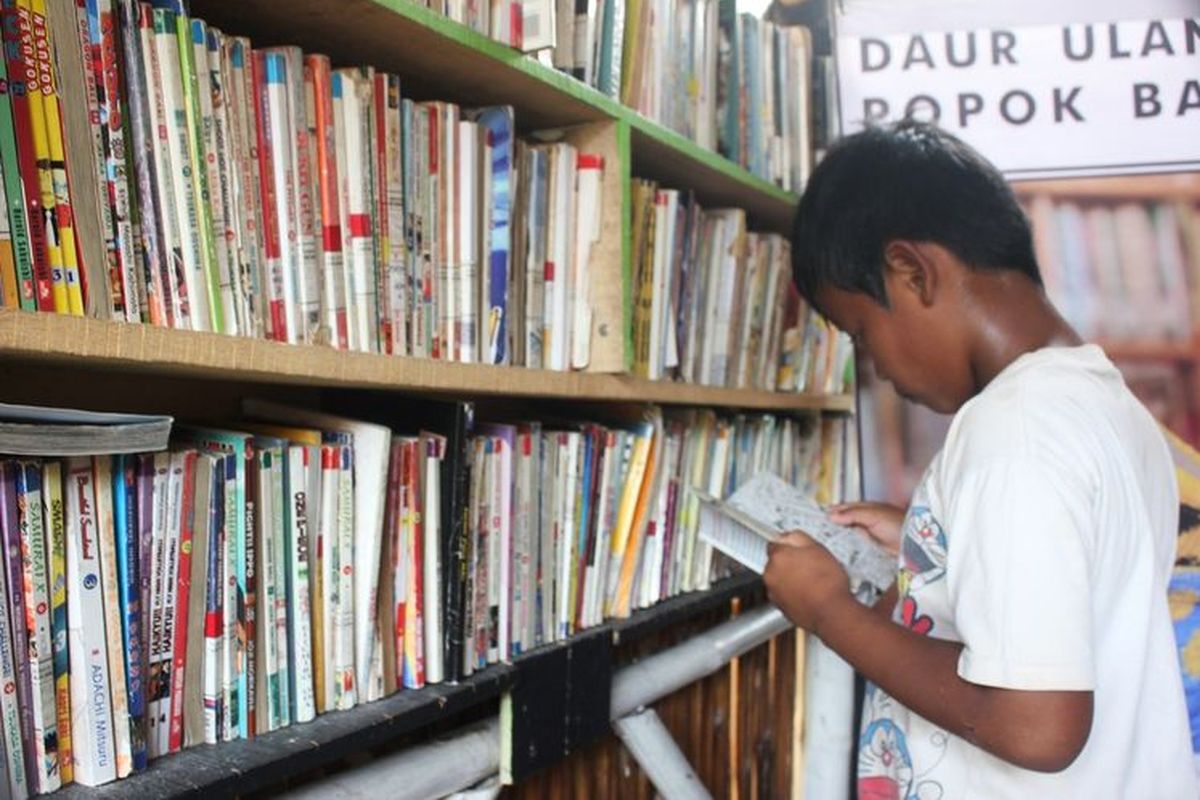 Seorang anak sedang serius membaca buku di Saung Baca Cianjur, Jawa Barat yang didirikan mantan cleaning service, Sandi Mulyadi (36)