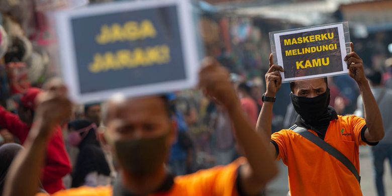 Petugas pengelola pasar melakukan sosialisasi pencegahan COVID-19 dengan membawa poster berisi pesan di Pasar Jatinegara, Jakarta, Kamis (11/6/2020). Upaya tersebut untuk meminimalisir kasus penularan atau penyebaran COVID-19 terjadi di pasar.