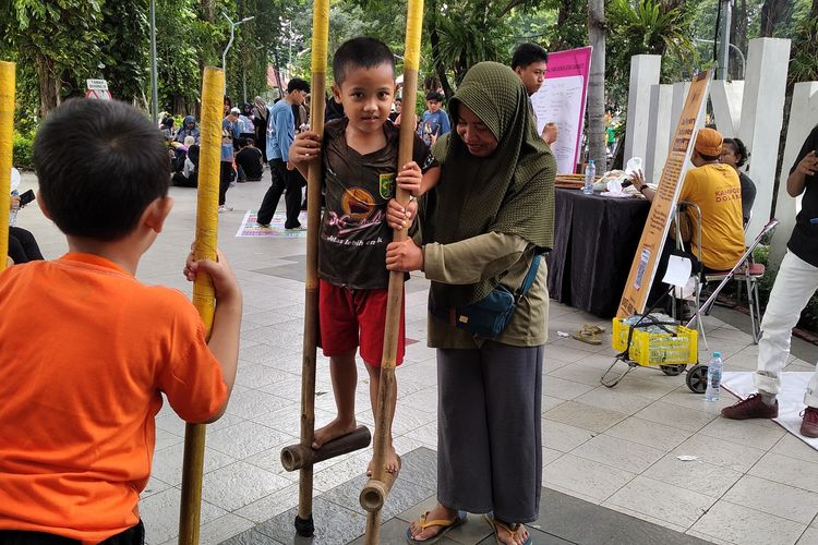 Faizan bersama ibunya, Lupi saat pertama kali mencoba egrang di event Car Free Day (CFD) Taman Bungkul, Surabaya, Minggu (23/2/2025)
