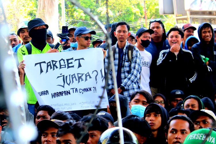Salah seorang peserta aksi membawa tulisan yang dilakukan saat menggelar aksi demo kepada manajemen tim didepan kantor marketing Persebaya Surabaya yang berada di Sutos Surabaya, Jawa Timur, Senin (30/10/2023) pagi.