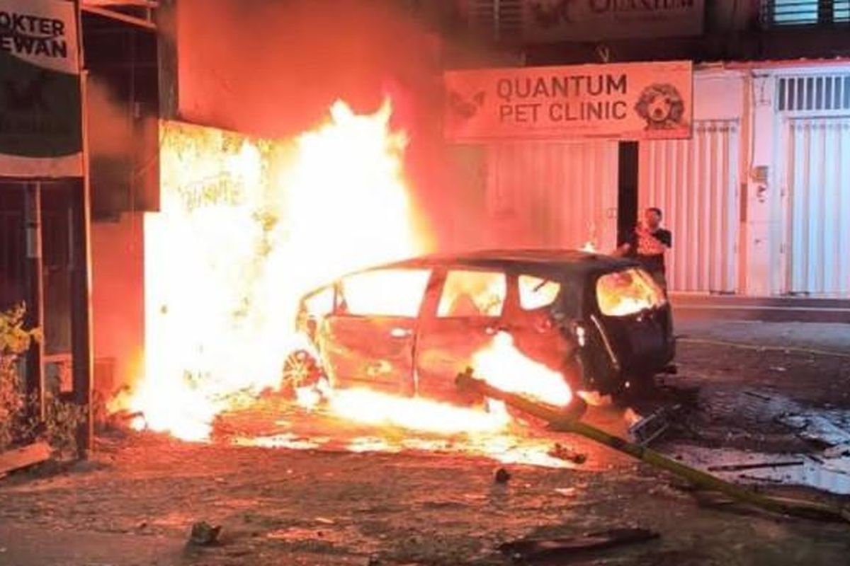 TERBAKAR - Mobil Honda Jazz ludes terbakar usai menabrak pohon dan lapak bensin eceran di Jalan Danau Bratan Kelurahan Sawojajar Kecamatan Kedungkandang Kota Malang, Rabu (16/7/2025). Akibat kejadian tersebut, pengemudi mobil mengalami luka bakar dan dievakuasi ke Rumah Sakit Saiful Anwar (RSSA).