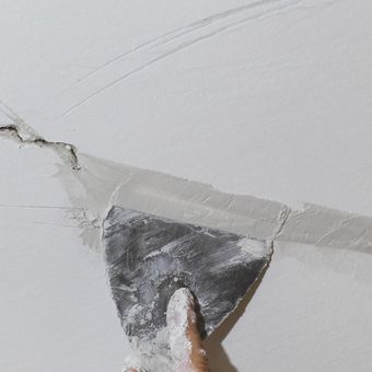 Ilustrasi memperbaiki dinding retak dengan plester. 