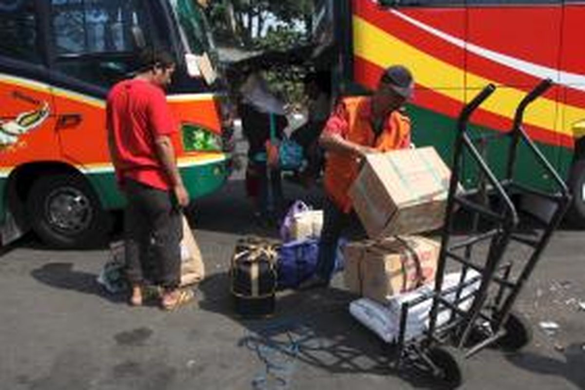 Penjual jasa porter, Wawan, menata barang bawaan warga yang turun dari bus di Terminal Kalideres, Jakarta Barat, Minggu (26/8). Arus mudik dan balik menjadi berkah bagi mereka untuk menambah penghasilan.