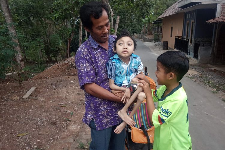 Dengan digendong ayahnya, Dimas bermain bersama tetangganya. 