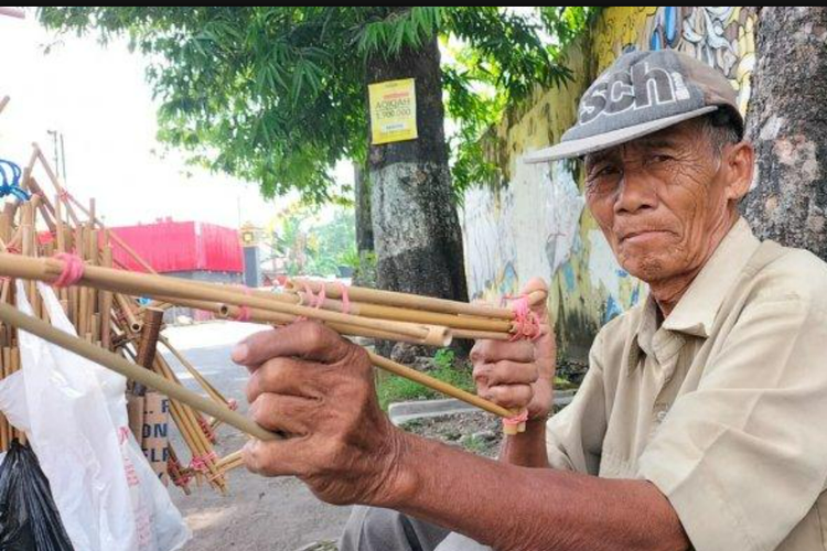 Jumiran, warga Madiun, Jawa Timur, merantau ke Sragen, Jawa Tengah, untuk berjualan pistol mainan bambu atau jepretan, Senin (27/6/2022). (Dokumentasi Tribunsolo.com). 