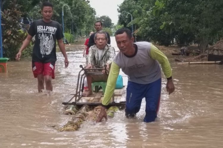 Seorang kakek yang mengalami stroke dievakuasi dengan perahu buatan warga di Balerejo, Kabupaten Madiun, Jawa Timur, Kamis ( 7 / 3 / 2019).