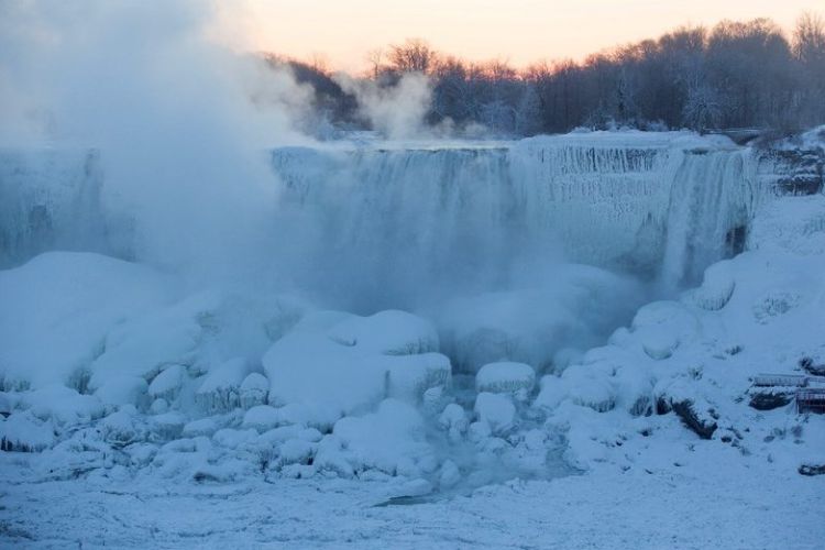 Uap muncul Air Terjun Niagara sebelum matahari terbit  di, Ontario, Kanada, Kamis (31/1/2019). Cuaca ekstrem membuat sebagian Air Terjun Niagara membeku. (AFP/Lars Hagberg)