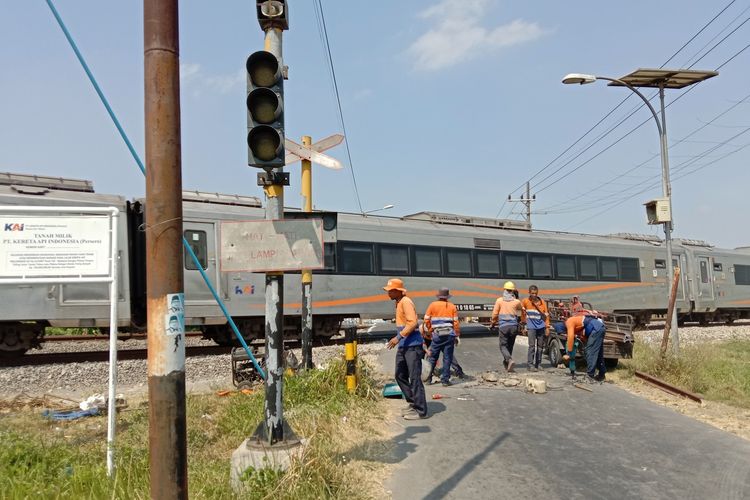 PERLINTASAN: Petugas PT KAI memasang batang besi sebagai penutup akses kendaraan roda 4 di pelintasan kereta api tanpa palang pintu.