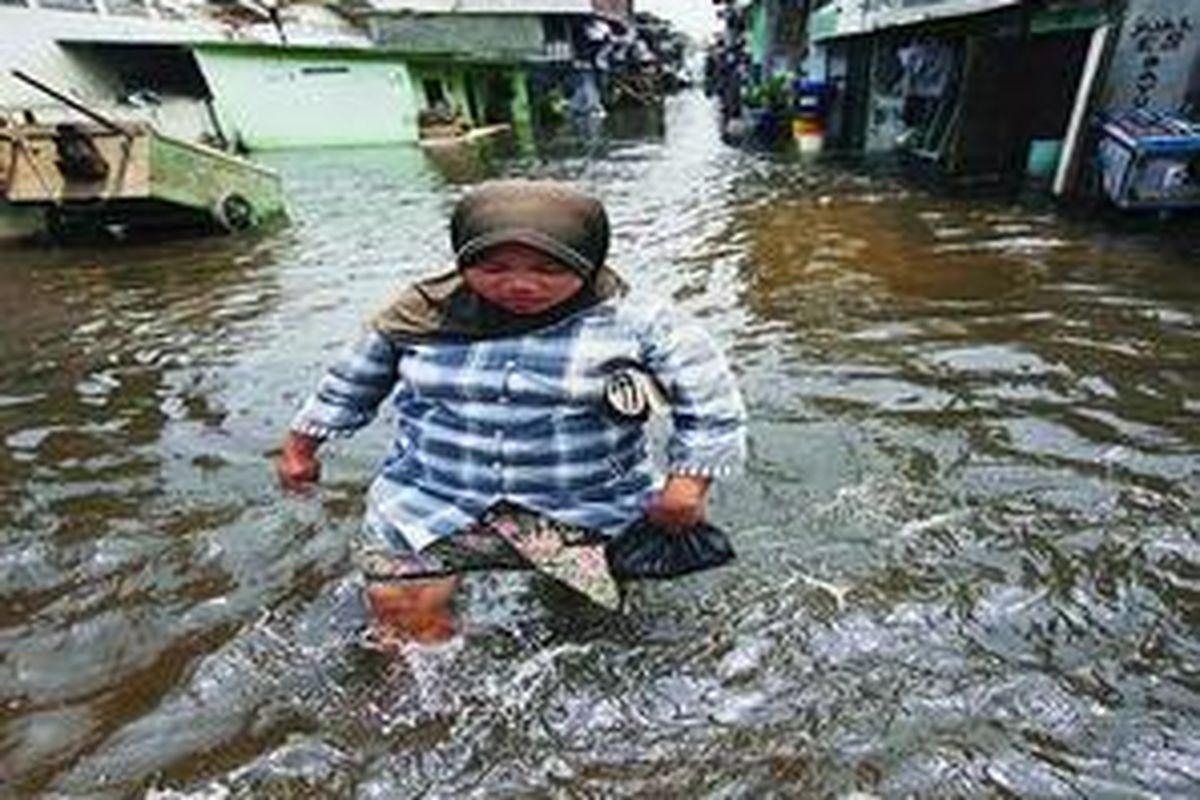 Warga berjalan melintasi genangan rob di kawasan Muara Baru, Penjaringan, Jakarta Utara, Jumat (6/11). Dalam empat hari terakhir ini, kawasan Muara Baru tergenang rob setinggi lutut orang dewasa sehingga mengganggu aktivitas warga.
