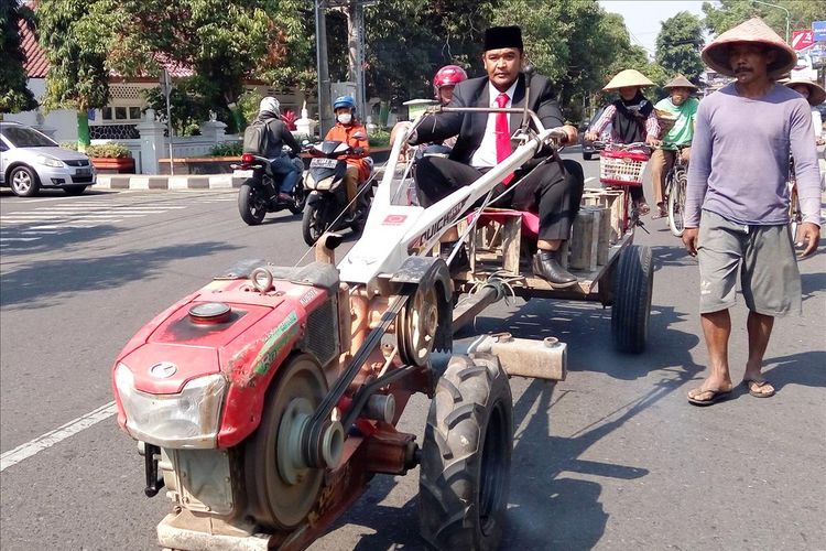 Wawan Prasetia saat mengendarai traktor menuju Pendapa Parasamya, Pemkab Sleman tempat digelarnya acara pelantikan anggota DPRD Sleman, Senin (12/8/2019). 