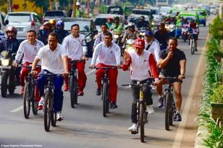 Presiden Joko Widodo melambaikan tangan saat bersepeda di acara car free day di Bogor, Minggu (18/10/2015) pagi.